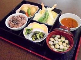 赤飯に汁物、天つゆ、天ぷらの盛り合わせ、煮物、あえ物などがそれぞれ器に盛られている。