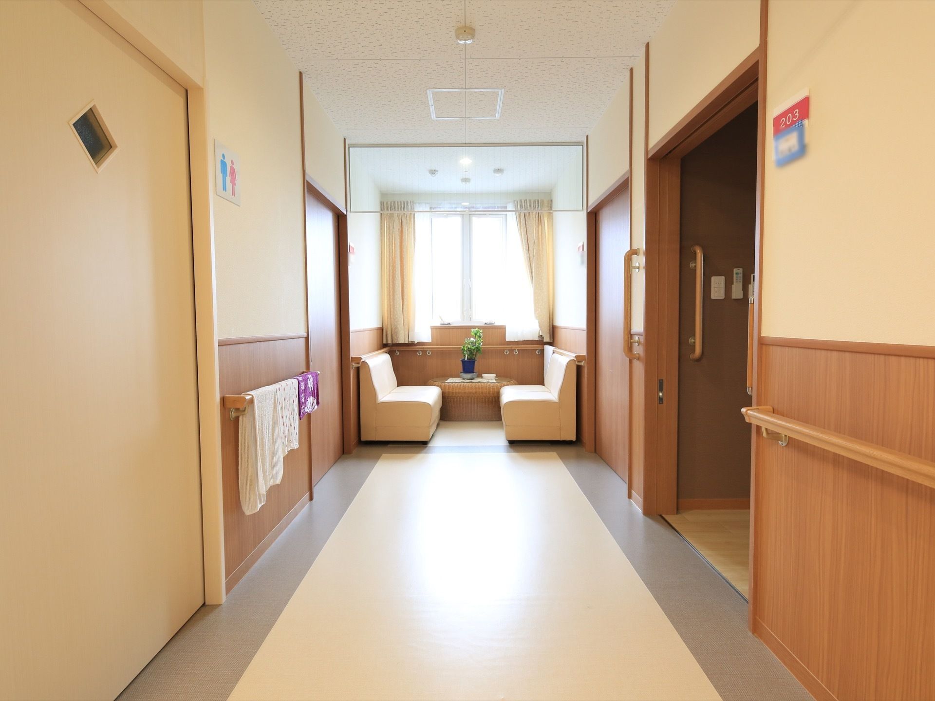 通路突き当りにカーテンの掛けられた腰高窓があり、その前に向かい合わせに2人掛けのソファーが置かれている。