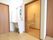 居室の出入り口扉の脇に洗面台があり、隣に縦向きに取っ手がついた引き戸のトイレがある。洗面台にはタオル掛けがある。