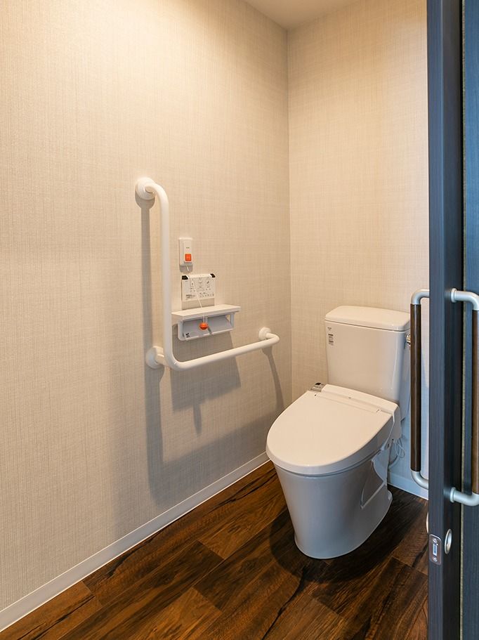 呼び出しボタンがついたトイレにはエル字型の手すりがあり、フローリングで介助スペースも広くとっている。