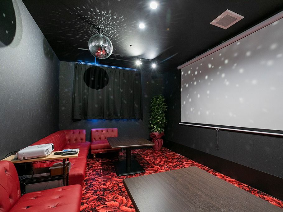 ミラーボールが飾られたシアタールーム。赤いソファが部屋の壁際に置かれ、大きなスクリーンが設置されている。