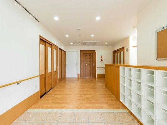 玄関へ入ると大きな靴箱や収納棚、エレベーターがあり、左手には手すりが付いている。