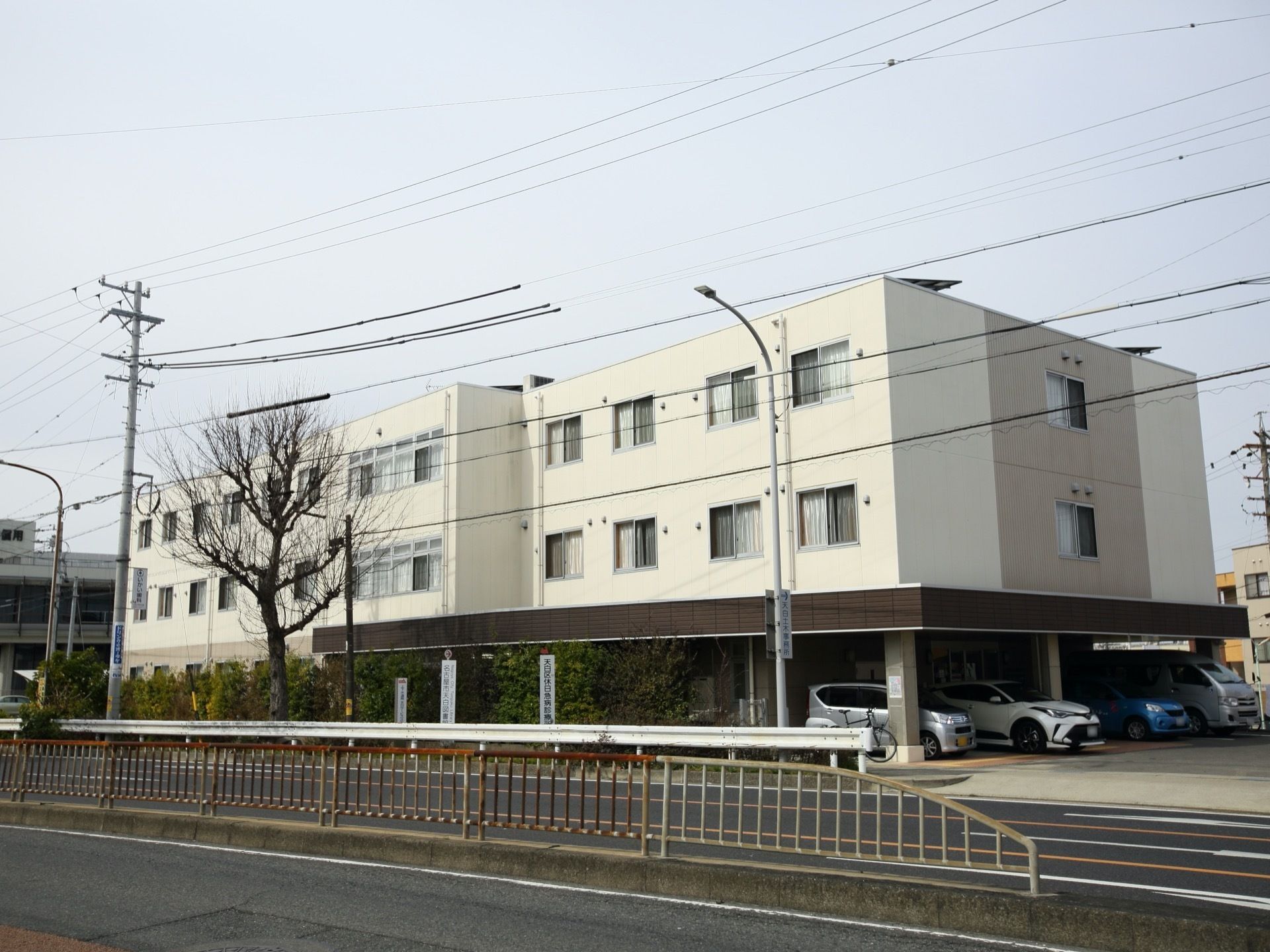 ３階建ての建物で、白い外壁の施設である。１階部分は駐車場になっており、たくさんの自動車が停まっている。