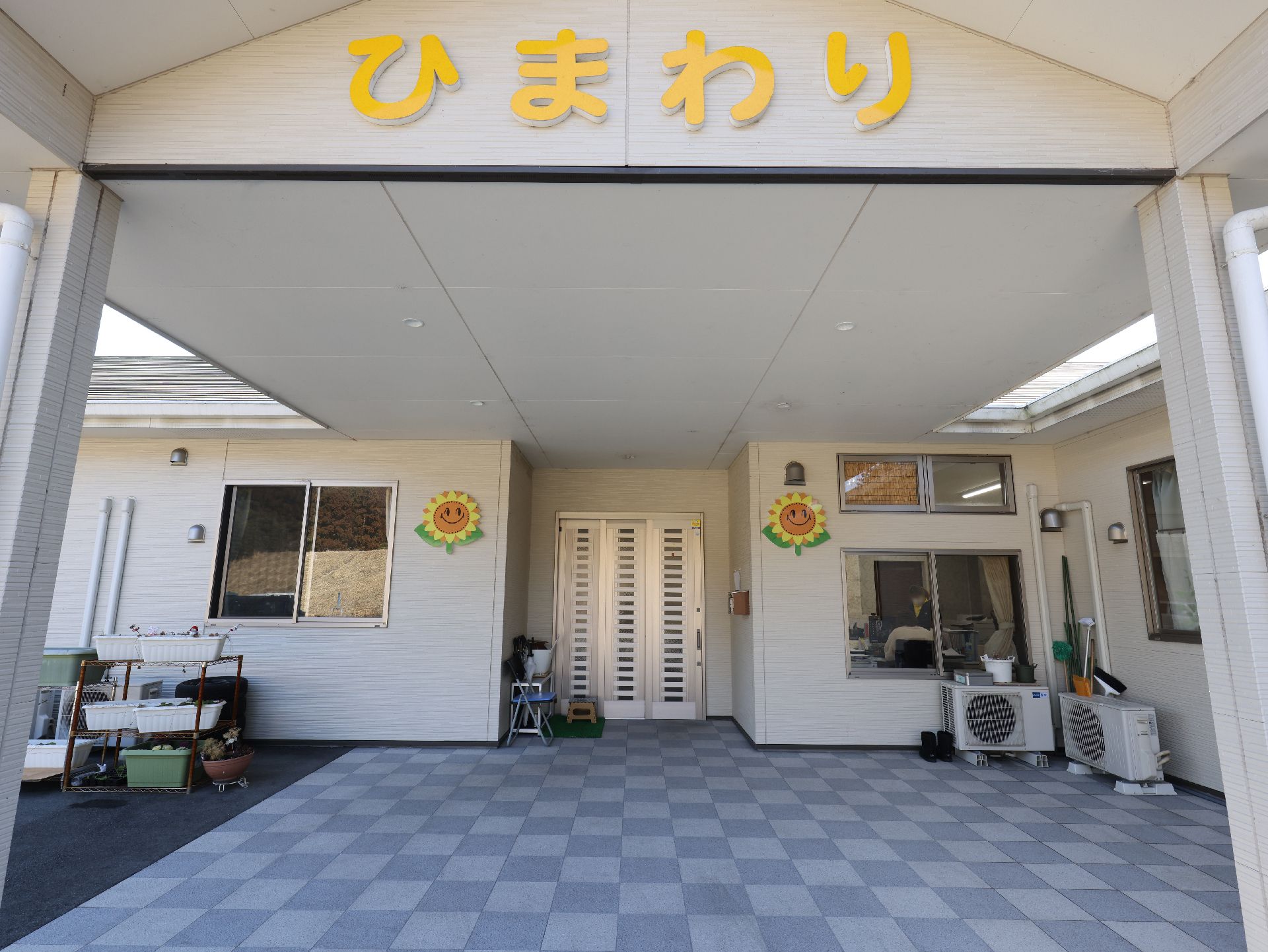 福祉車両の手すりを掴み、降りようとしているスタッフのサポートをしているエプロンを付けた男性スタッフ。