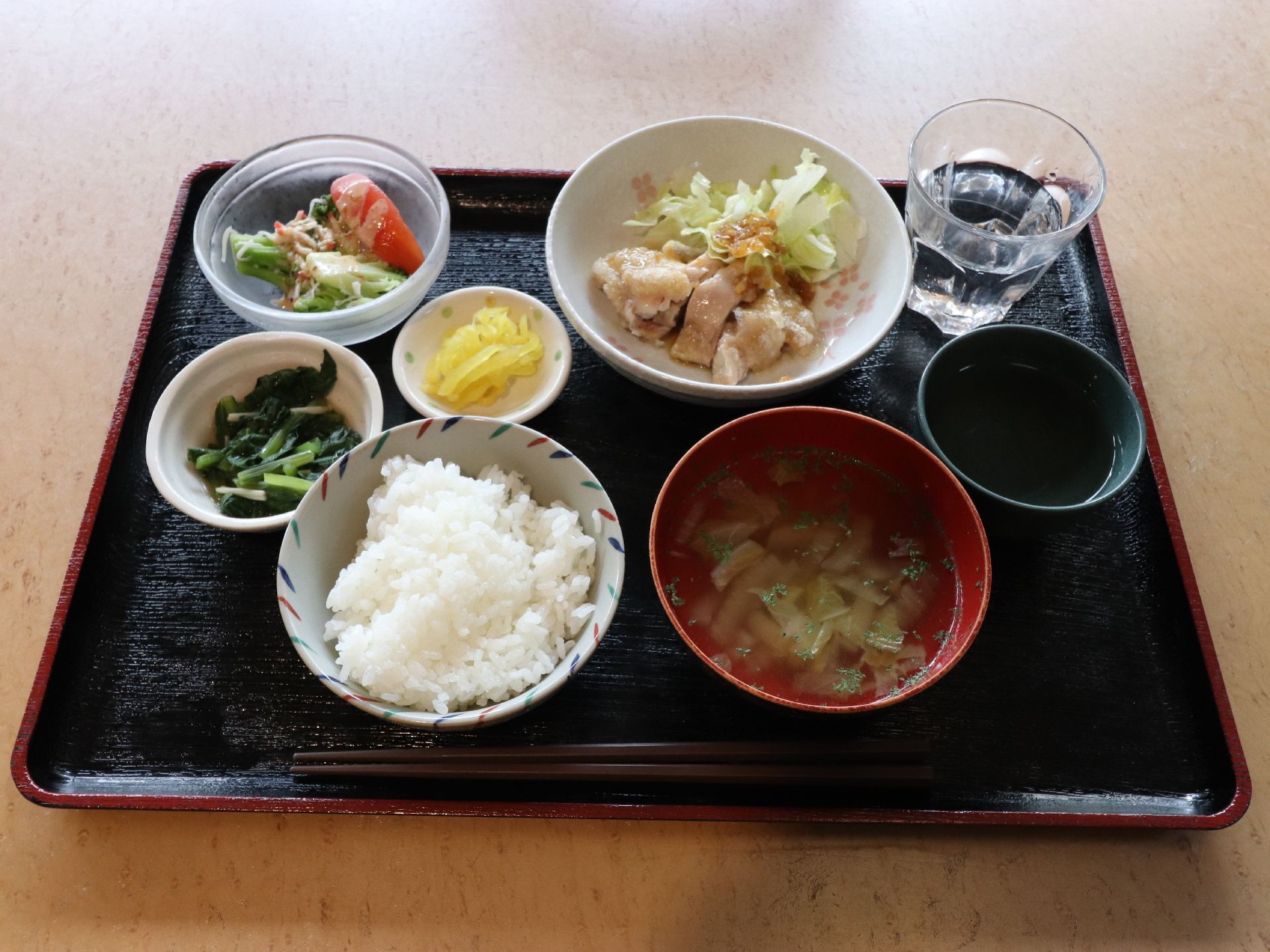 鳥肉等のたんぱく質と青菜やトマト等の野菜を中心とした栄養バランスが考えられたメニューが彩りよく配膳されている。