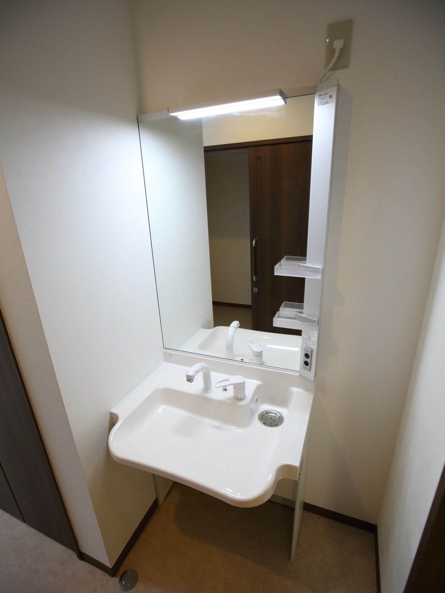 居室の洗面台は鏡が大きくシンプルなデザインである。収納棚は最小限になっているので、掃除もしやすい。壁と同じ白で統一されている。