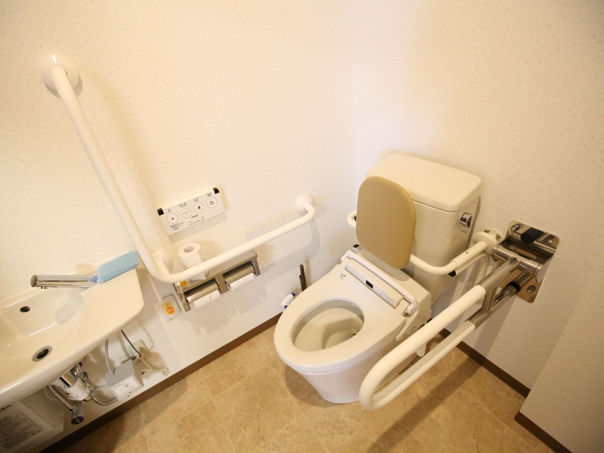 背もたれが取り付けられた蓋の無い洋式便器の両側に手すりが設置されているトイレ