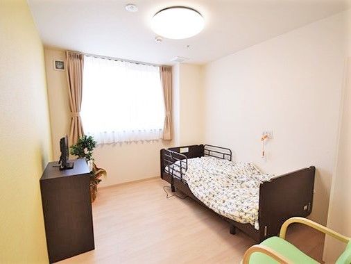 寝具がセットされたベッドやいす、タンスなどが置かれた居室には緊急通報装置も付いている。