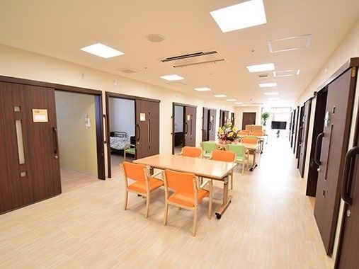 居室が両サイドにあり、萬納の広い廊下にダイニングテーブルが並び、テレビも置かれている。