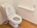 清潔感のあるトイレである。立ち座りの際に掴まることのできる手すりや、緊急時の呼び出しベルが設置されている。