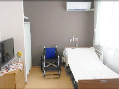 介護ベッドが置かれた部屋には車いすやテレビもあり、タンスの上にはヒマワリも飾られている。