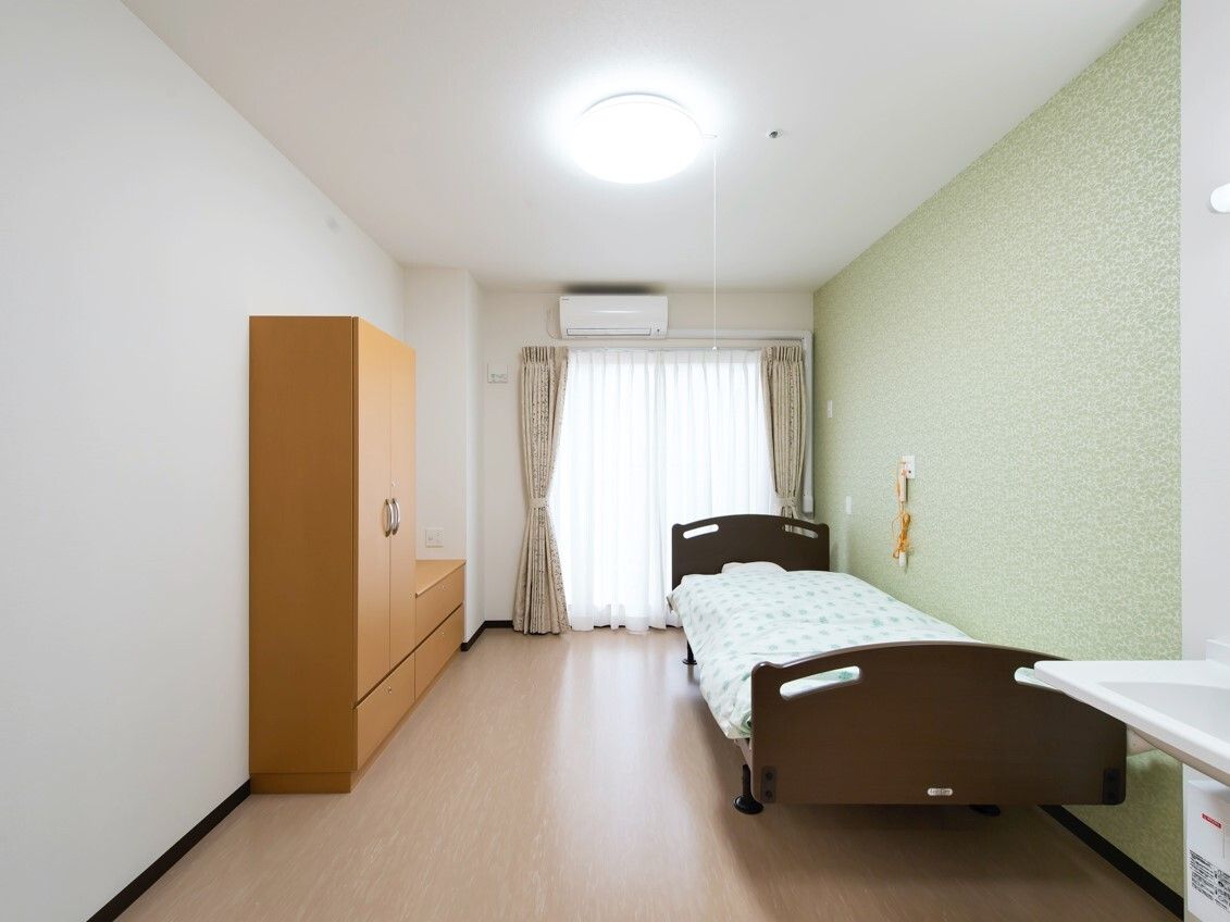 クローゼットが付いたフローリングの部屋には寝具付きのベッドが置かれ、エアコンも付いている。