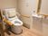隅々まで清掃が行き届いた清潔感のあるトイレである。右側の壁には、温水洗浄用の操作ボタンや大型の手すりが付いている。