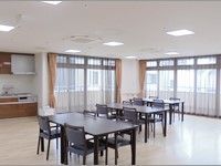 広めのスペースに四人掛けの椅子とテーブルが並んでいる様子。二面採光の明るい部屋