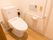 温水洗浄便座器が完備されているトイレの壁には、L字型手すりと緊急呼び出しブザー、ペーパーホルダーが設置されている。