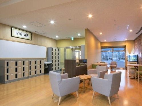 手洗い場や扉付きの靴箱が設置されたエントランスを入ると、グレーの椅子が設置された応接スペースや水槽が置かれたカフェスペースがある。
