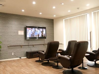 ゆったりとくつろげる落ち着いた雰囲気の鑑賞スペースには黒いいすが壁掛けテレビの前に置かれている。