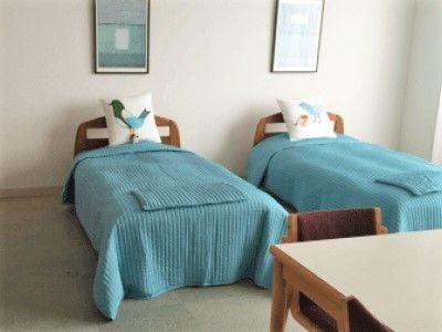 空色のベッドカバーがかけられたベッドが２つ並んだ二人部屋。