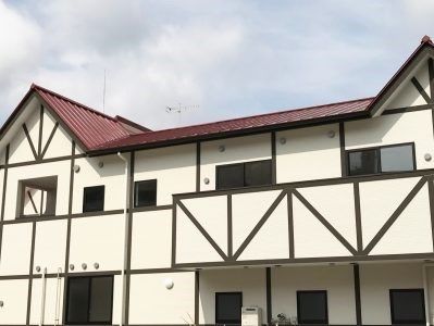 ２階建ての建物の２階部分にはベランダがつき、えんじ色の三角屋根もある。