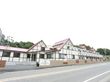 白の外壁に黒のラインが映える二階建ての施設。施設の周りにはピンクベージュの塀が建てられており、塀に施設名の看板が設置されている。