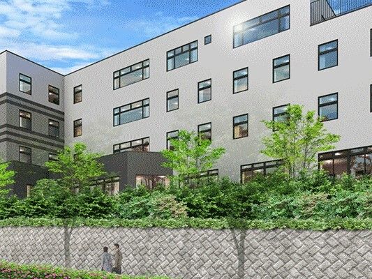 エル字型のグレー系の建物は4階建て。高台にあり、日当たりのいい場所に建っている。