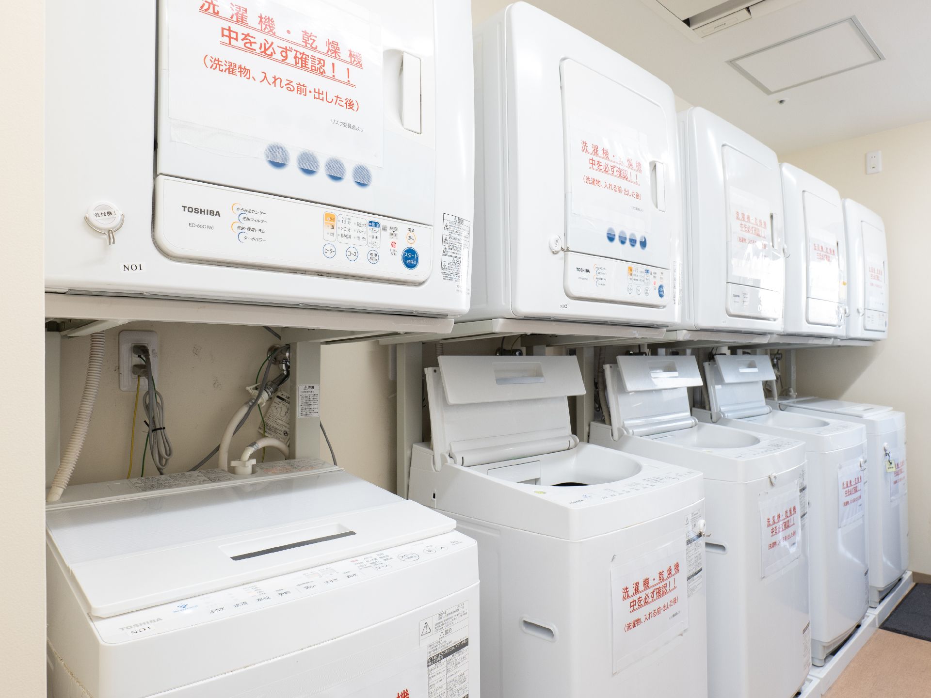 洗濯機と乾燥機が設置され、物干し竿も置かれているランドリー