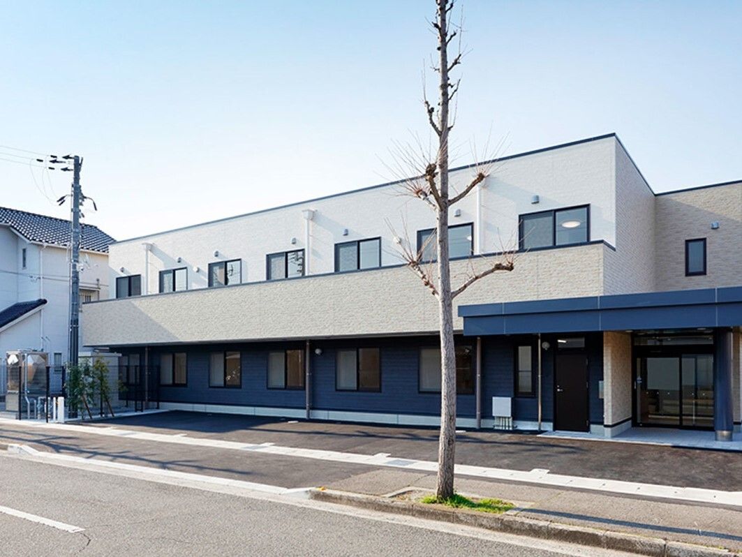 白を基調とした横に長い2階建ての建物は日当たりのいい場所に建っていて、2階部分にはベランダがある。