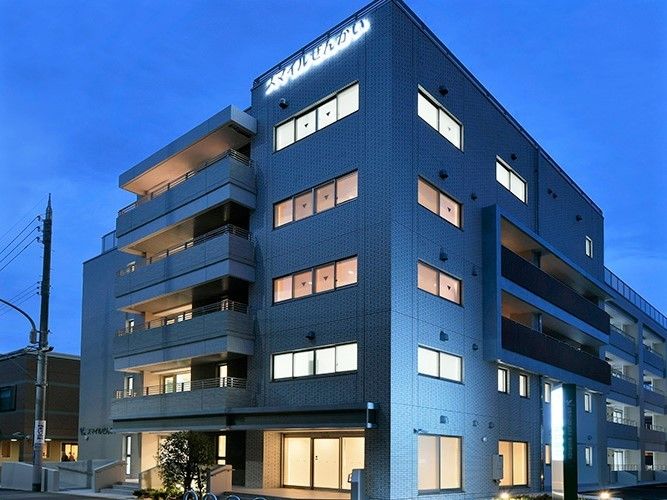 薄暗くなりライトアップされた建物。窓が多く、外壁の施設名もライトアップされている。