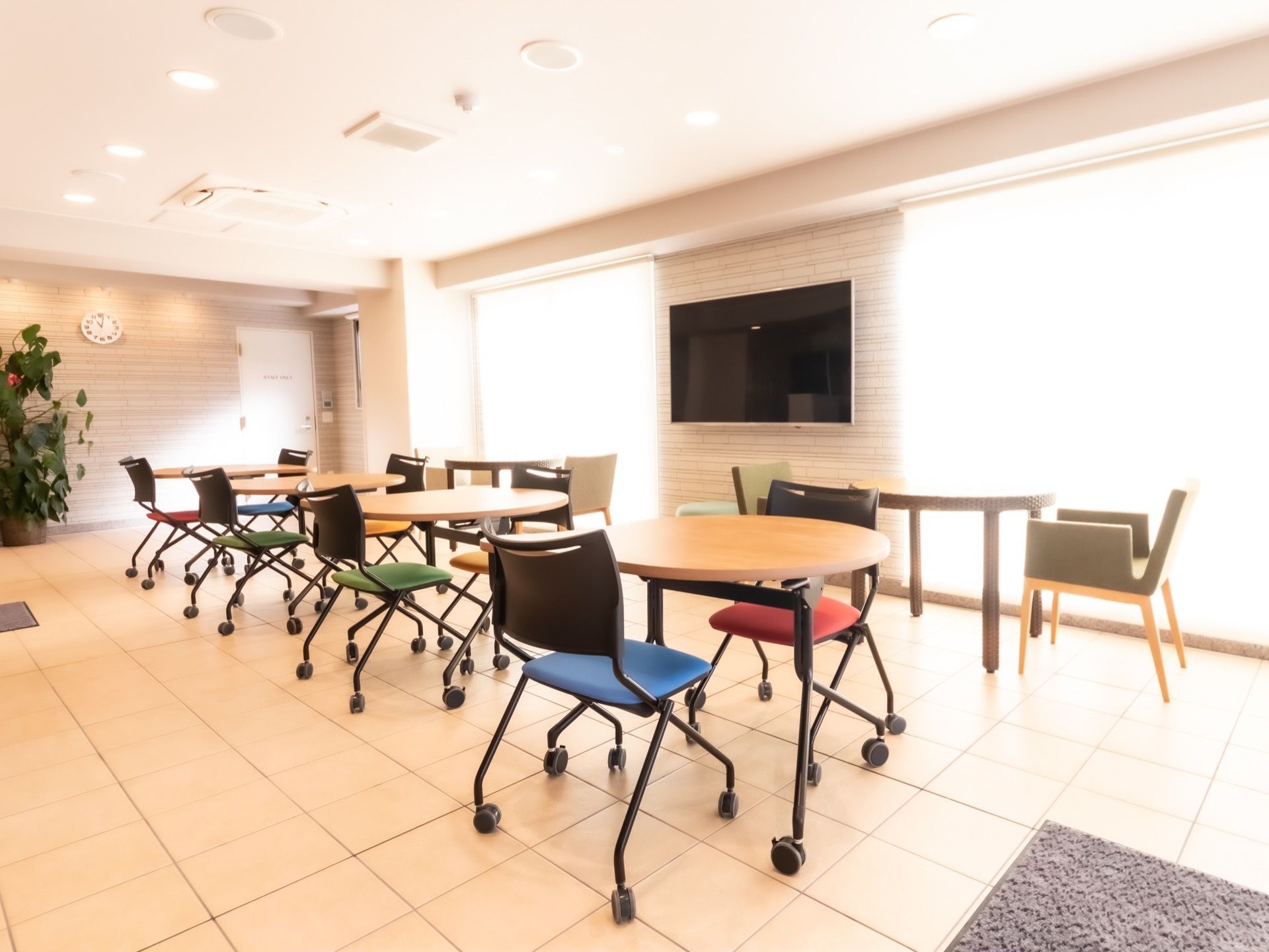 室内には窓から日が差し込み、明るく落ち着いた雰囲気。カフェテーブルが複数設置され、気軽に交流の場として活用できる。