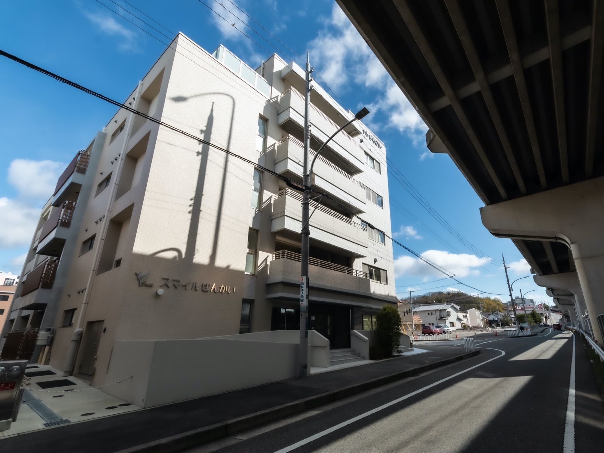 白い外装の５階建ての建物が、高速道路沿いに建てられている。２階以上は日当たりがとてもよく、快適に過ごせる。