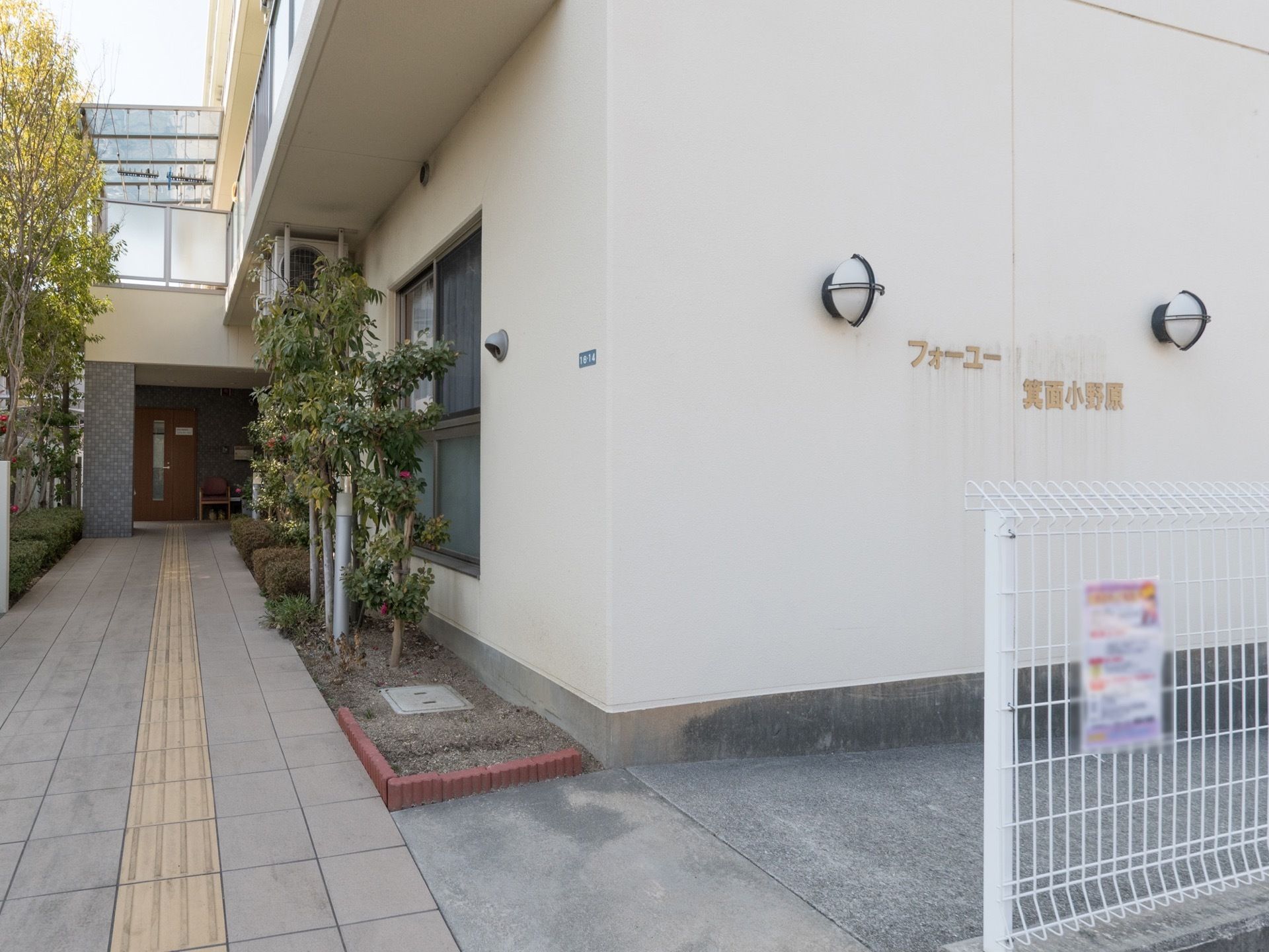 外壁に表示された施設名は照明で照らされるため、夜間でもお間違いなくご来館いただける。エントランスまでの植栽は手入れが行き届いている。