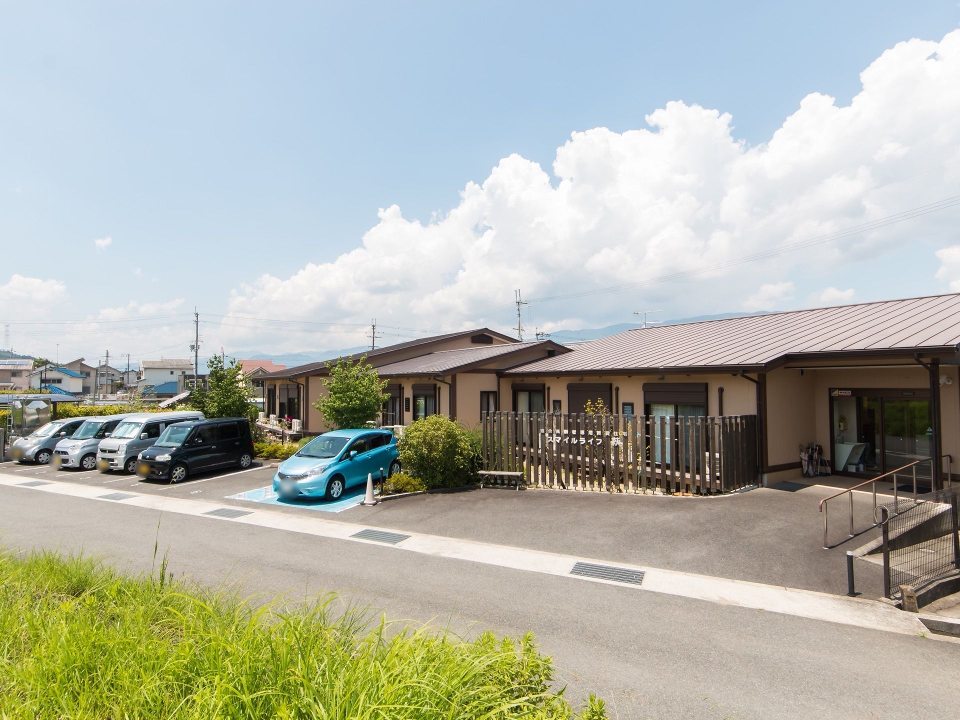 施設はアットホームな落ち着きのある平屋建てである。エントランスまでは手すりが完備されている。周辺は緑の多いのどかな環境である。