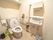 広いトイレ空間に洋式便器が設置されている。手前に手洗器が備えられており、手洗い用石けんのボトルやペーパータオルが周辺に用意してある。