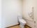 広いスペースの壁際にトイレが設置されている。壁に、便座機能の操作パネルやトイレットペーパーホルダーが付けられている