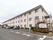 横に長い構造の３階建ての施設である。建物の前に白線で仕切られた多くの駐車スペースがある。外階段が設置されている。