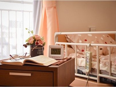 介護仕様のベッドと医調度品が置いてある部屋の様子。ベランダにつながる窓があるのが分かる
