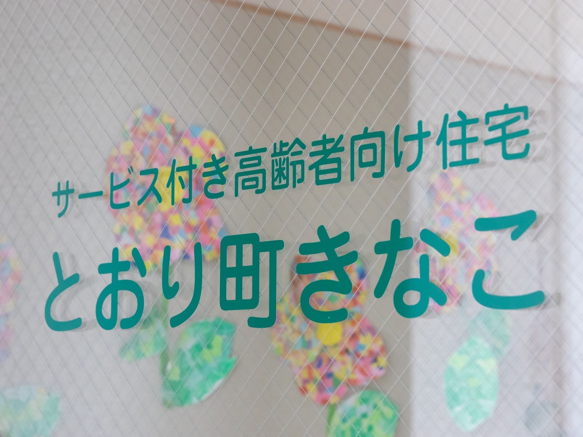 集合玄関はガラス戸で、住宅の名前が書かれている。飛散防止のためのワイヤー入りガラスが使用されている。