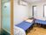 青いマットレスが敷かれた介護用ベッドが２台、小部屋に設置されている。天井付近にはエアコンがついている。