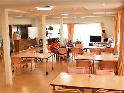 ４人掛けのテーブルと椅子が並んでいる場所。奥のほうにテレビ、窓があるのが分かる写真