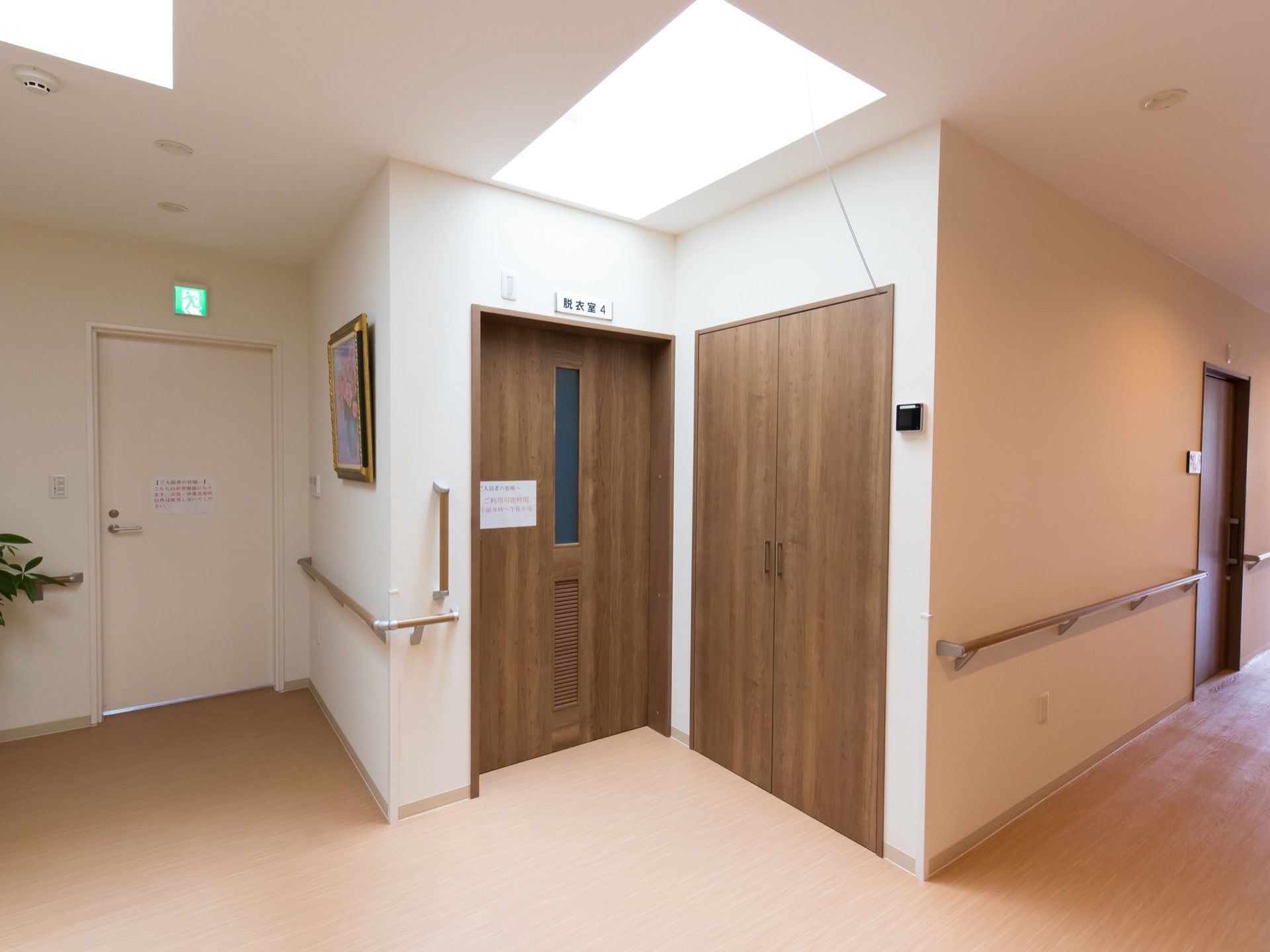 手すりが施された通路の一角に、脱衣所と表示された引き戸が設置されている。左側の奧には非常口が見える。