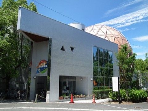 伊丹市立こども文化科学館は、ガラス張りの壁面を組み込んだグレーの石壁が近代的なデザインのエントランス部分と、背後にある球形の建造物が特徴的。