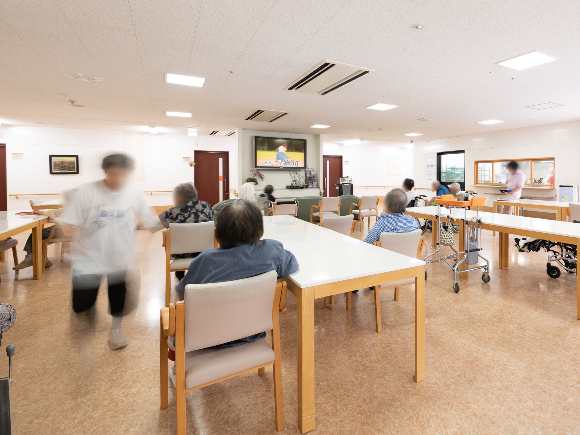 共有スペースは天井にエアコンを埋め込んでいる。壁に液晶テレビが設置され、テーブルセットが置かれている。