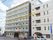 建物がつらなる街並みを写した写真。白い壁のビルと優しい色合いの建物が２つ並んでいる