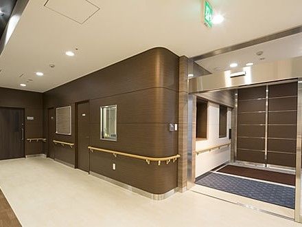 ホテルのような清潔な雰囲気の廊下の写真。絶え間なく手すりが取り付けられ、壁に絵画が飾ってある