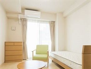 木製のベッドとソファが置いてある小さなワンルームの様子。施設内の居室スペース