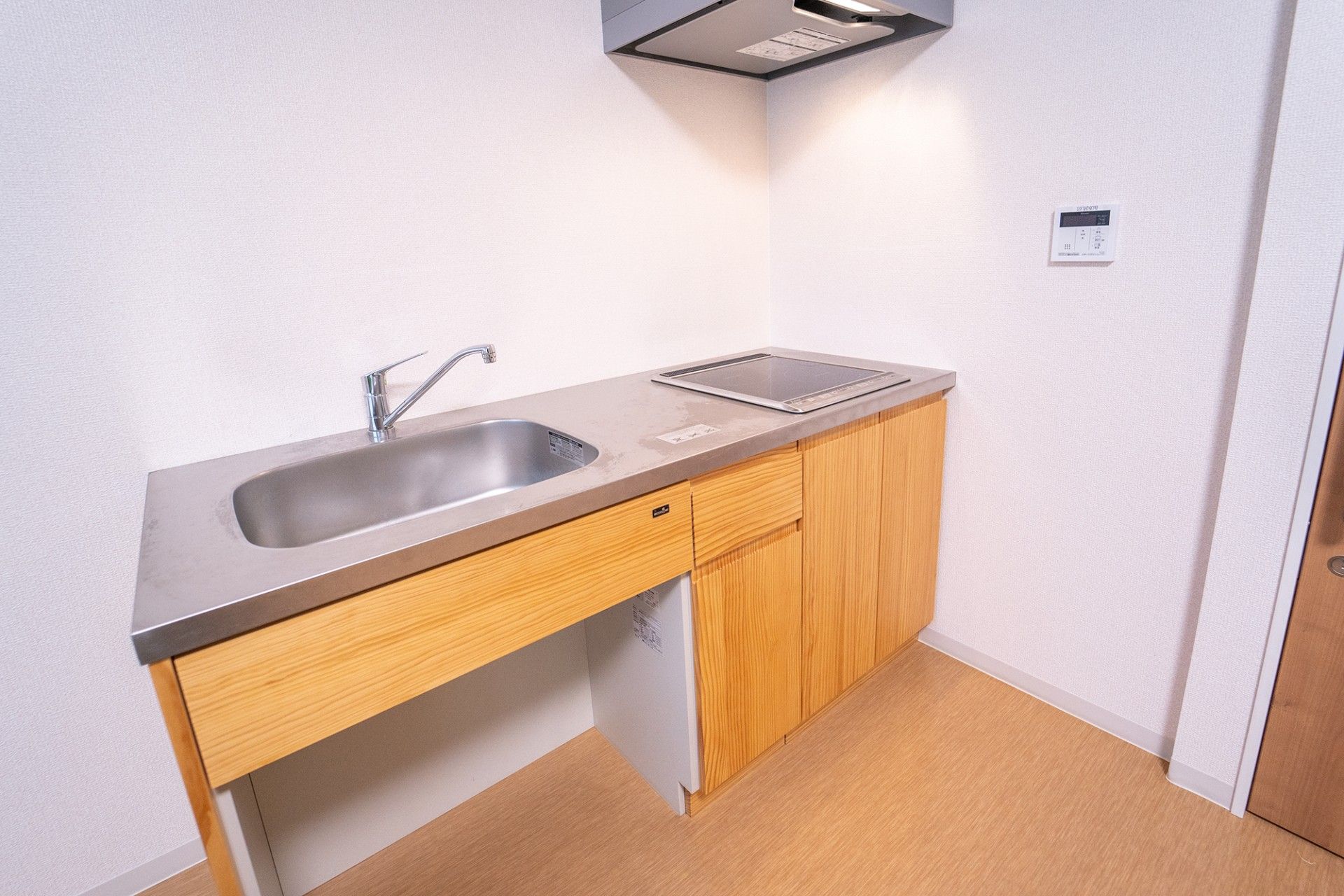 居室にはトイレと洗面台、小さな棚が備わっている。扉は横開きで間口が広い。段差のないフローリングである。