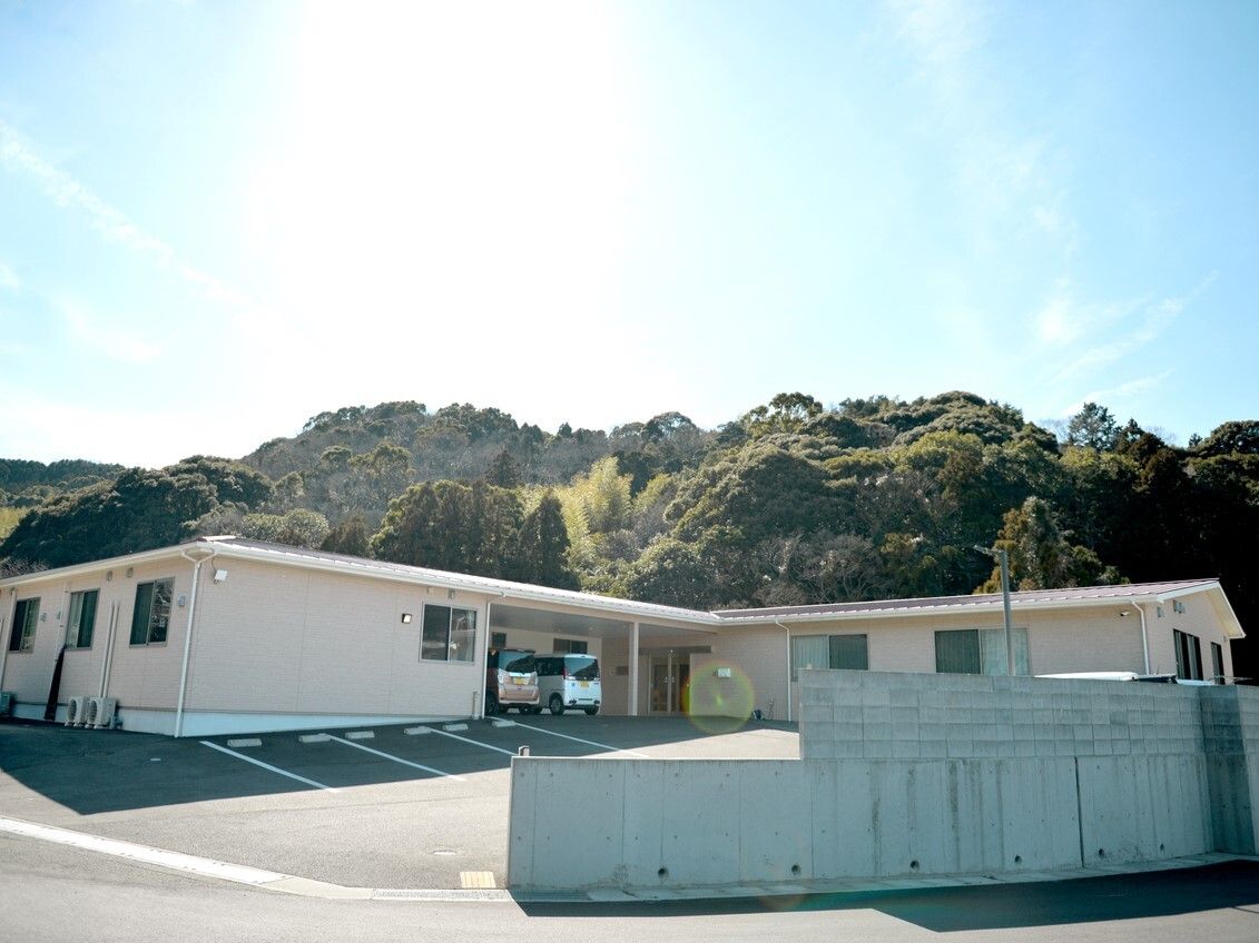 日当たりのいい場所に建っている平屋建ての建物。緑が多くある場所にあり、敷地内には駐車場がある。