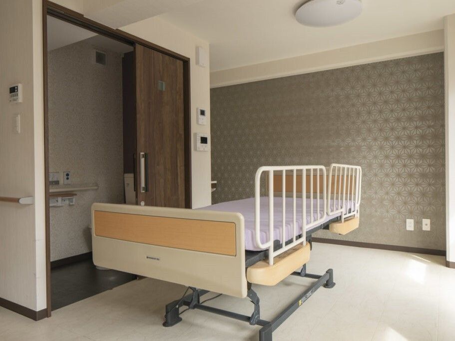 介護ベッドが置かれた部屋にはエアコンが付き、スライド式のドアが設置されたトイレがある。