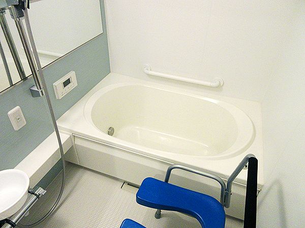 シャワーやシャワーチェアが付いた一人用の浴槽が設置された浴室には大きな鏡もある。