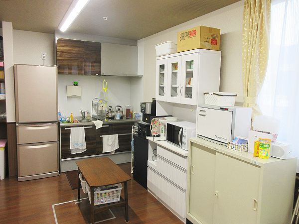電子レンジや冷蔵庫、食器棚などがあり、移動式のカートも中央に置かれているキッチン。